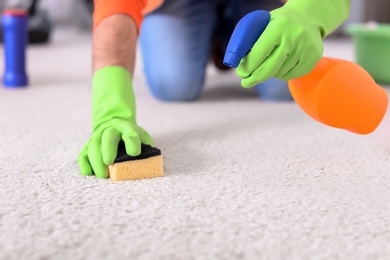 Photo of Young man cleaning carpet at home