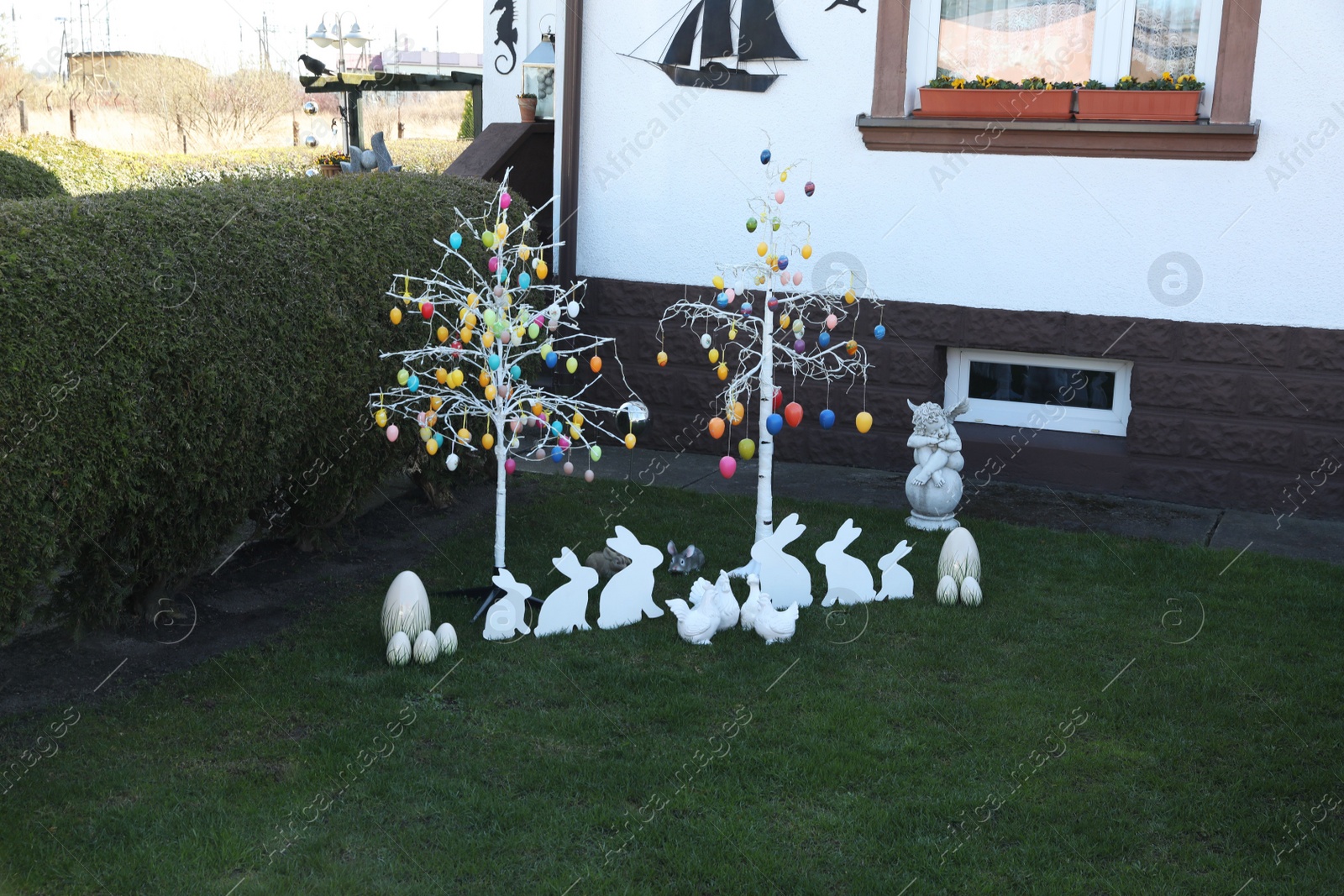 Photo of Trees with decorative eggs, chickens and bunnies at backyard. Easter celebration