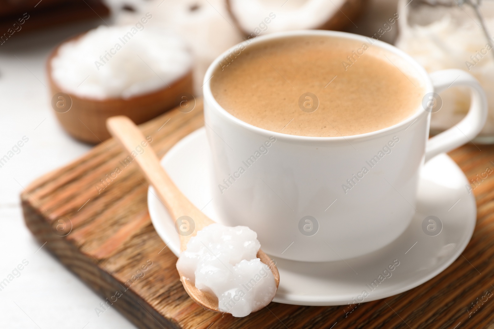 Photo of Delicious coffee with organic coconut oil on wooden board