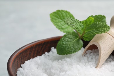 Photo of Natural sea salt in wooden bowl and scoop, closeup