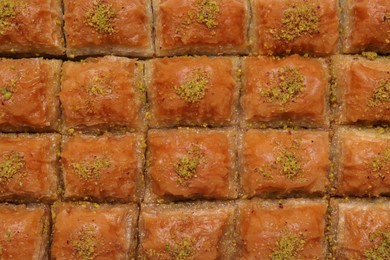 Photo of Delicious sweet baklava with pistachios as background, top view