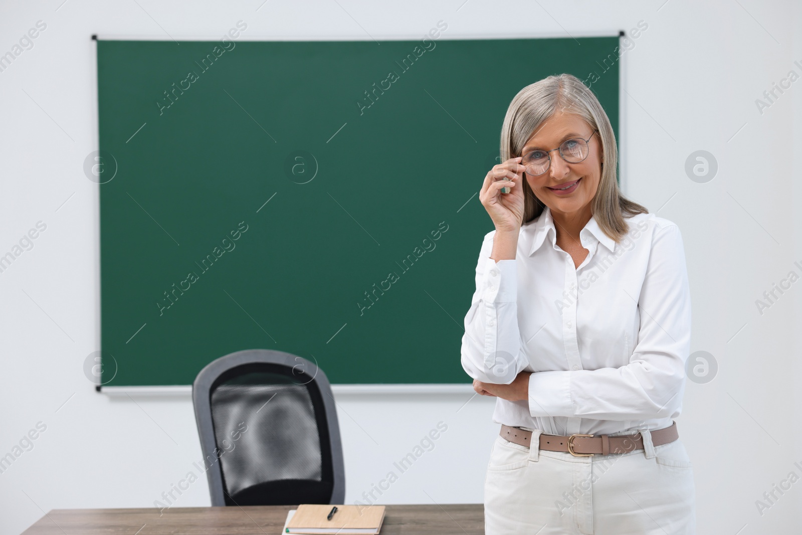 Photo of Portrait of professor near blackboard in classroom, space for text