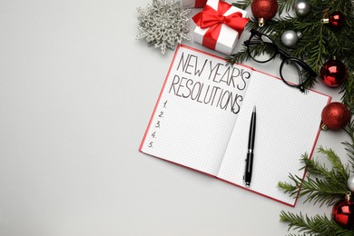 Photo of Making New Year's resolutions. Flat lay composition with notebook and festive decor on light background