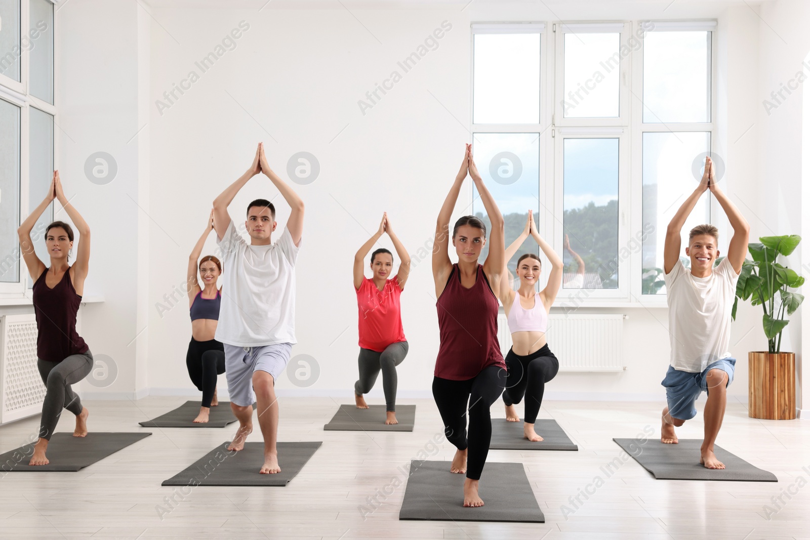 Photo of Group of people practicing yoga on mats indoors