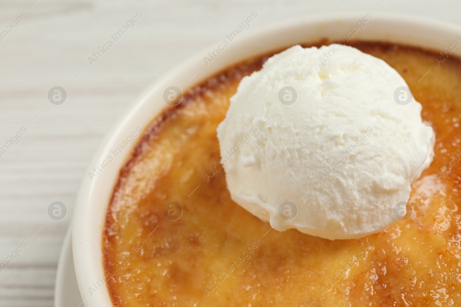 Photo of Delicious creme brulee with scoop of ice cream on white table, closeup. Space for text