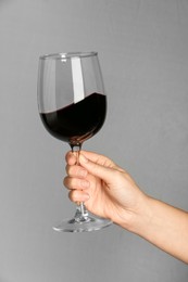 Photo of Woman with glass of red wine on grey background, closeup