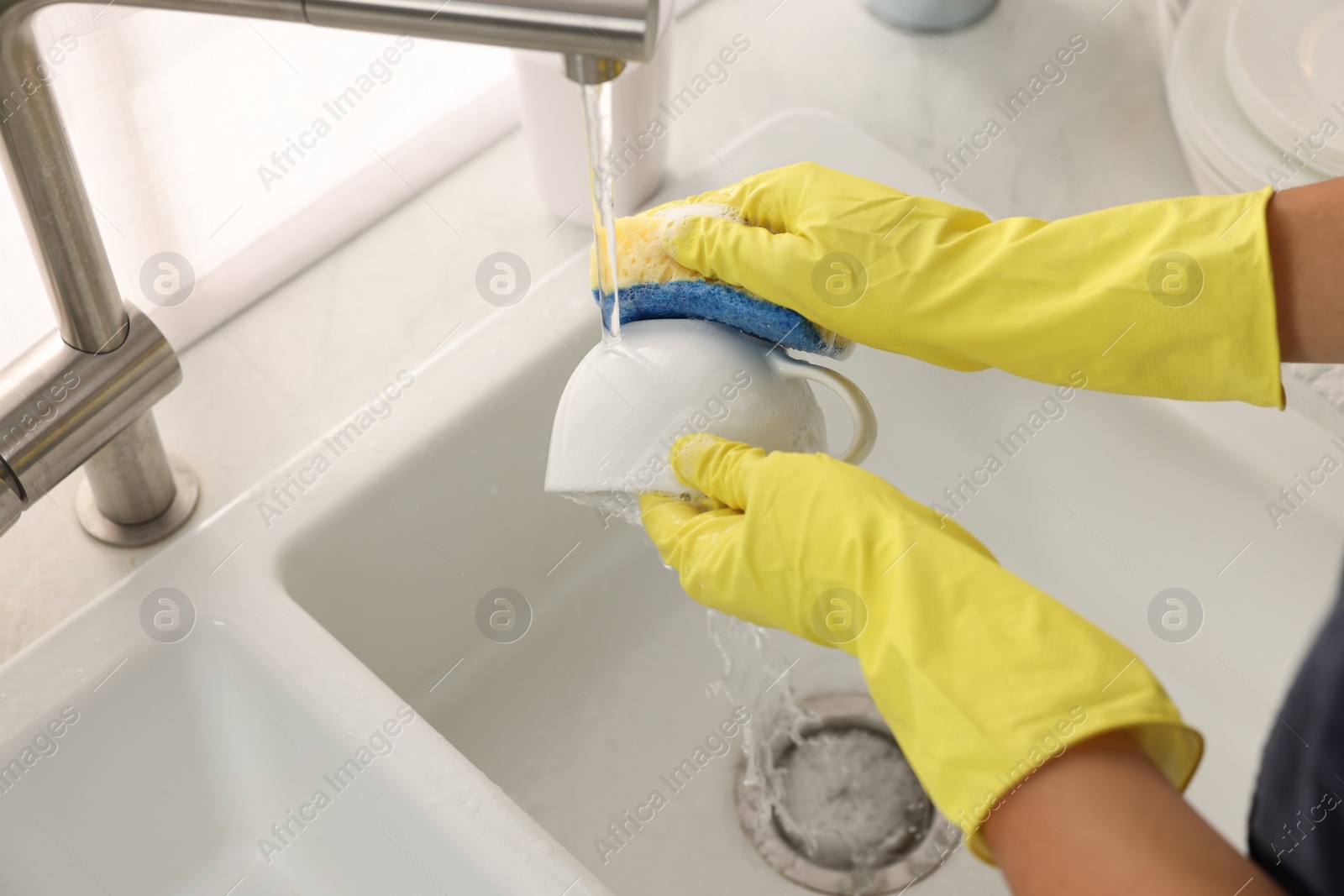 Photo of Woman washing cup at sink in kitchen, closeup