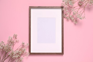 Photo of Empty photo frame and gypsophila flowers on pink background, flat lay. Space for design