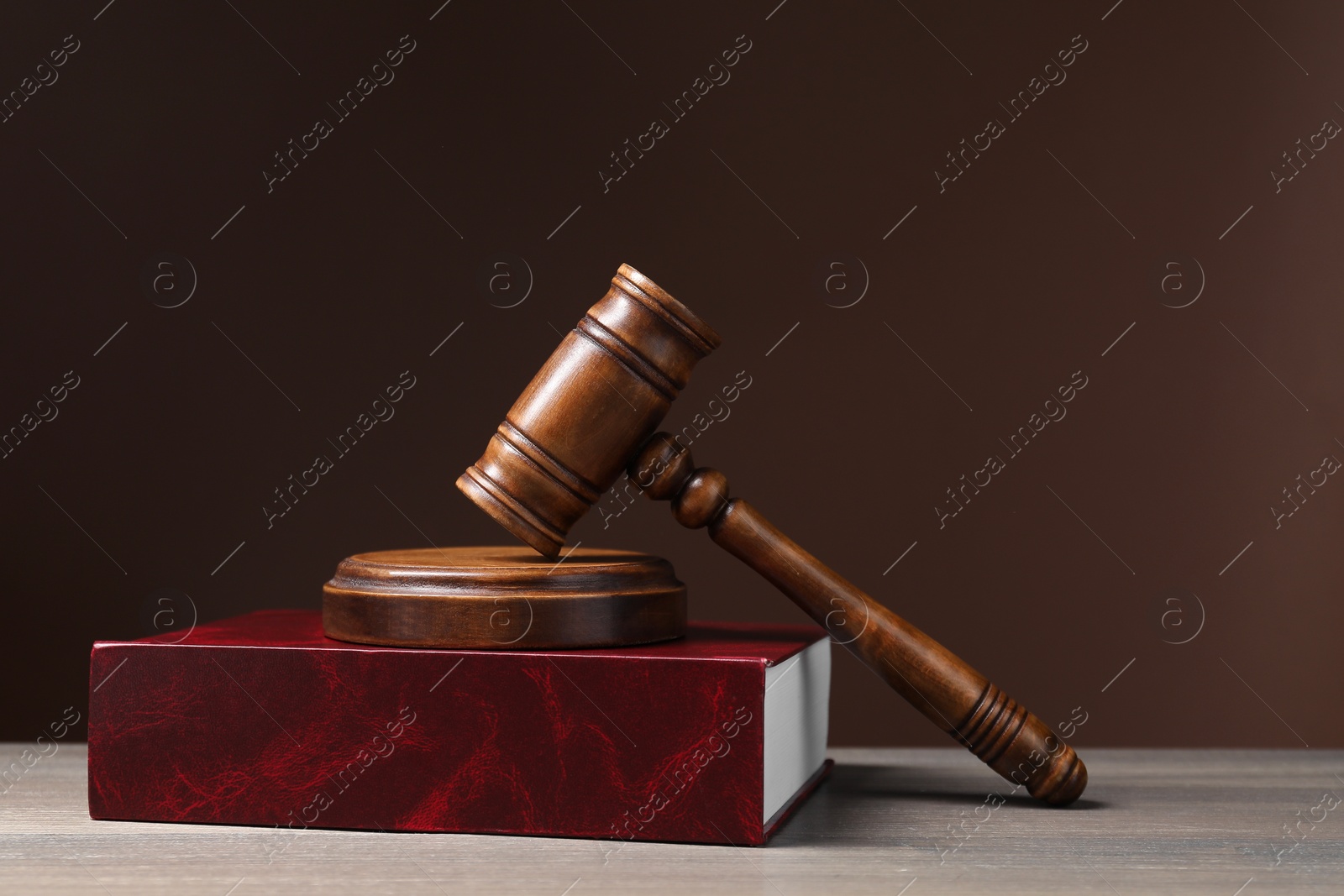 Photo of Law. Book and gavel on wooden table against brown background