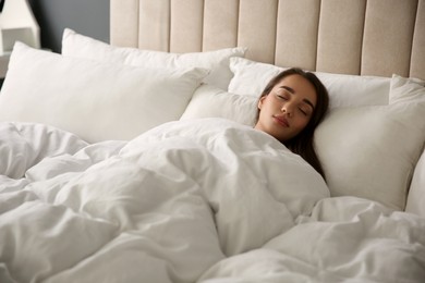 Photo of Beautiful young woman wrapped with soft blanket sleeping in bed at home