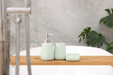 Photo of Set of bath accessories on tub in bathroom