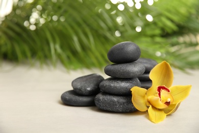 Photo of Spa stones with flower on table against blurred background. Space for text