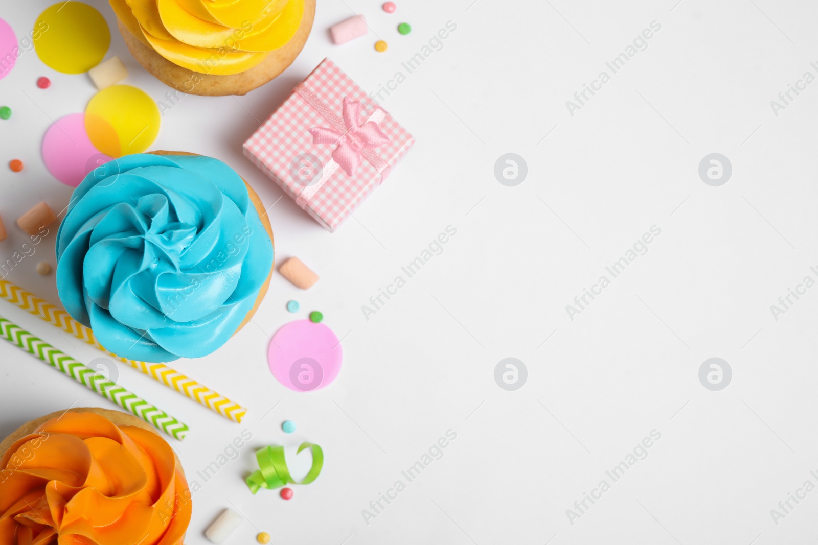 Photo of Flat lay composition with colorful birthday cupcakes on white background. Space for text