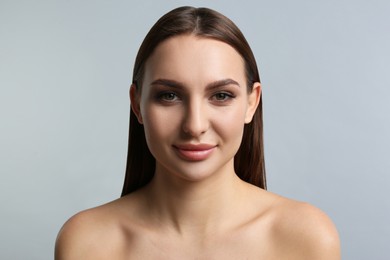 Photo of Portrait of beautiful young woman with plump lips on light grey background