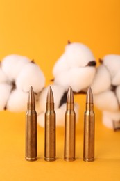 Photo of Bullets and beautiful fluffy cotton flowers on yellow background