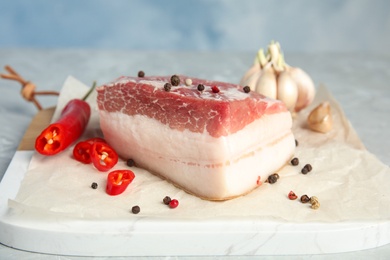 Photo of Composition with pork fatback and spices on board against blue background