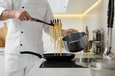 Photo of Professional chef cooking delicious pasta on stove in kitchen, closeup