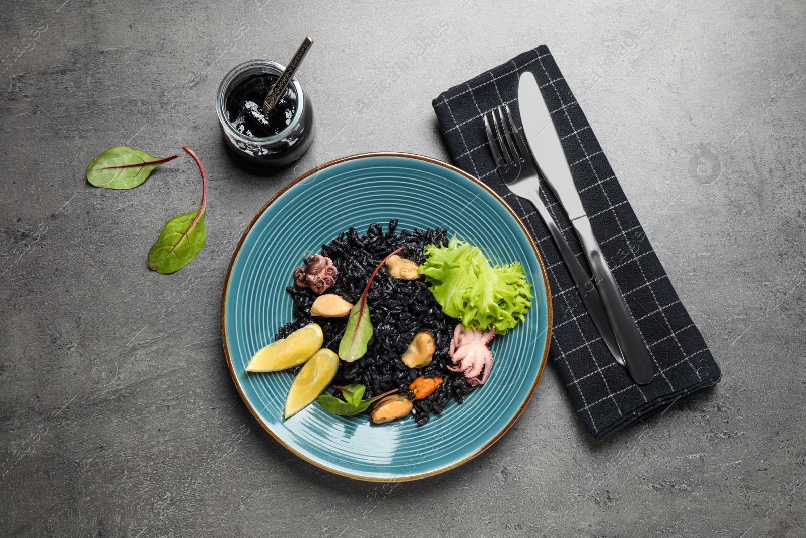 Photo of Delicious black risotto with seafood served on grey table