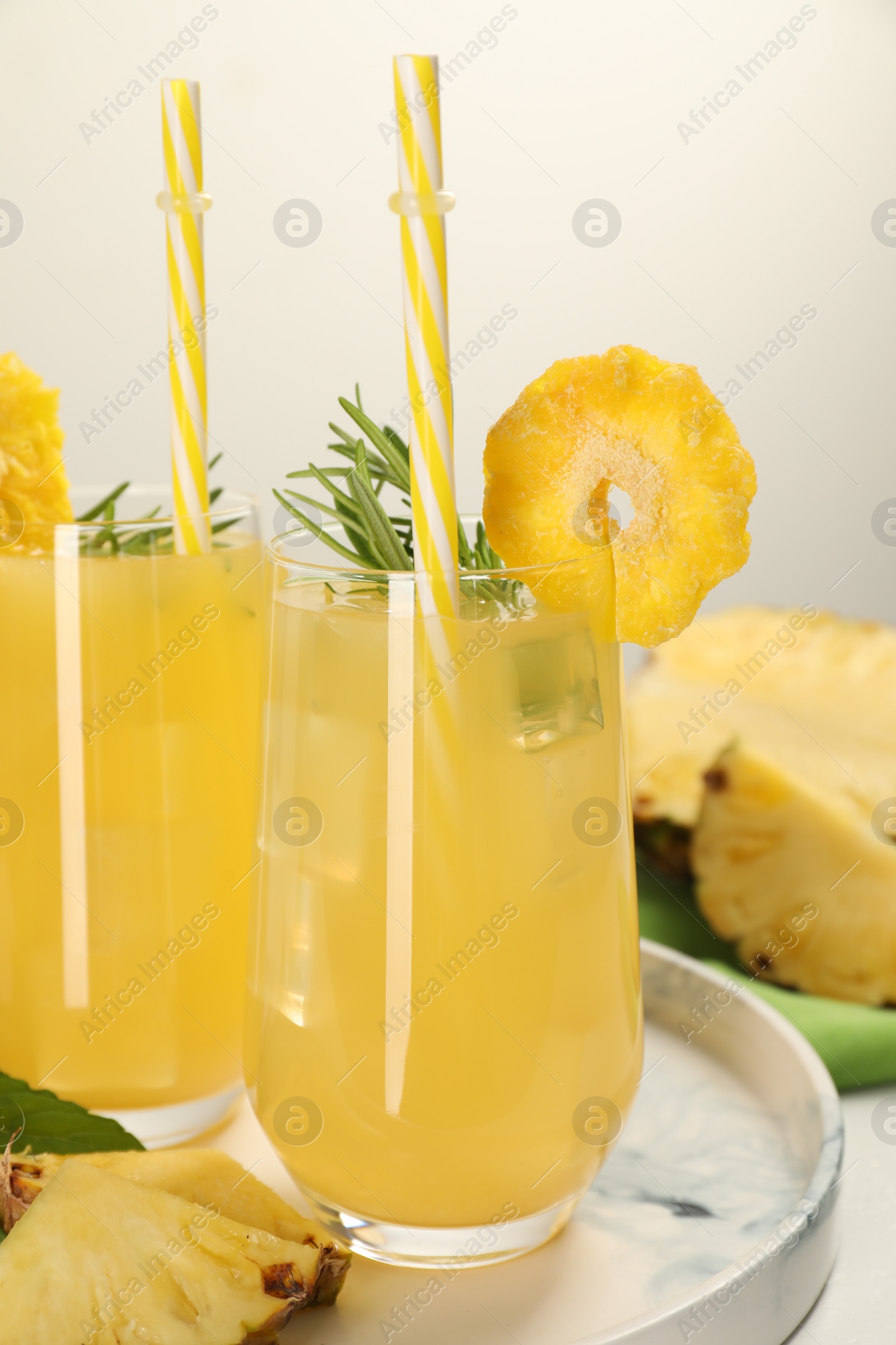 Photo of Glasses of tasty pineapple cocktail with rosemary on table, closeup