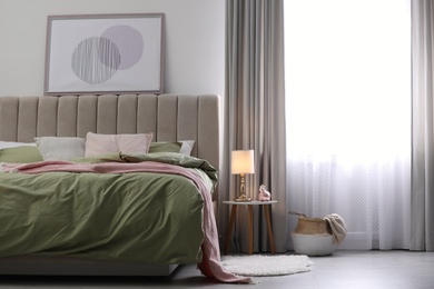 Photo of Comfortable bed with new pistachio linens in modern room interior