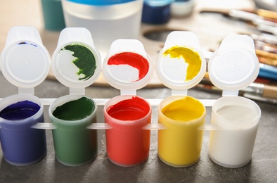 Photo of Different paints and brushes on grey table, closeup