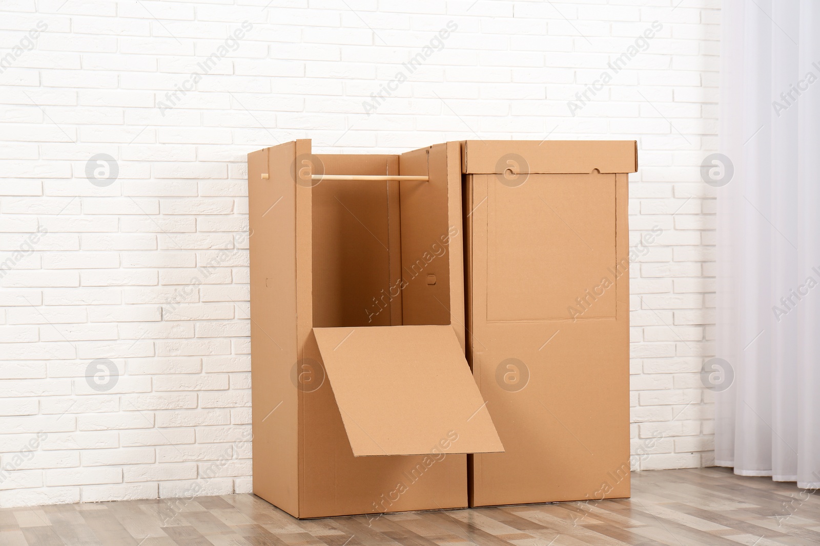 Photo of Empty cardboard wardrobe boxes against brick wall indoors