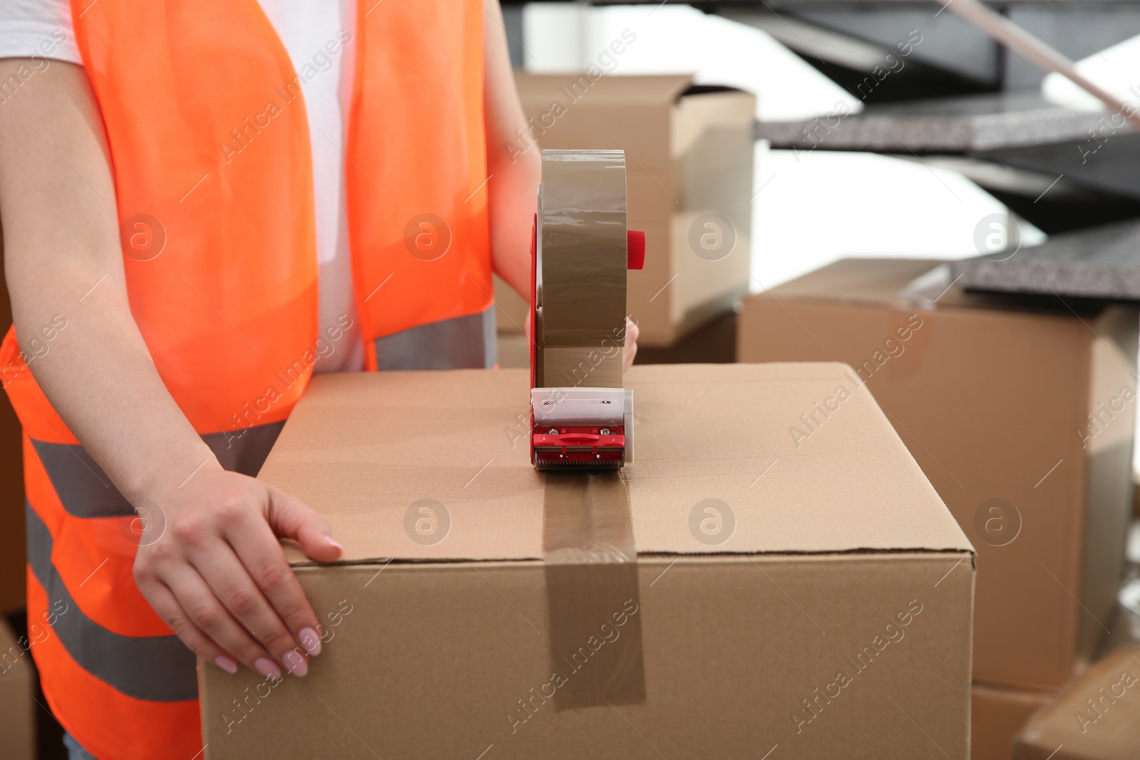 Photo of Worker taping cardboard box indoors, closeup view