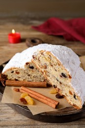 Photo of Plate of cut delicious Stollen sprinkled with powdered sugar and ingredients on wooden table