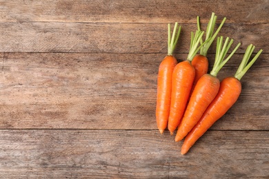Photo of Carrots on wooden background, top view. Space for text