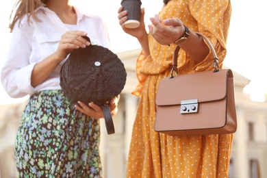 Young women with stylish bags on city street, closeup