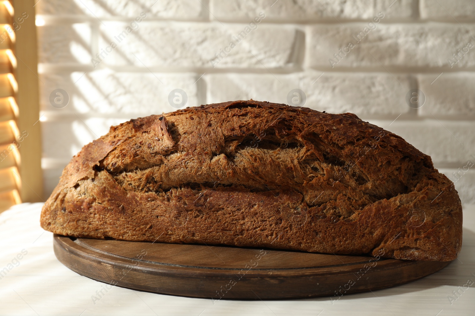 Photo of Freshly baked sourdough bread on white wooden table indoors