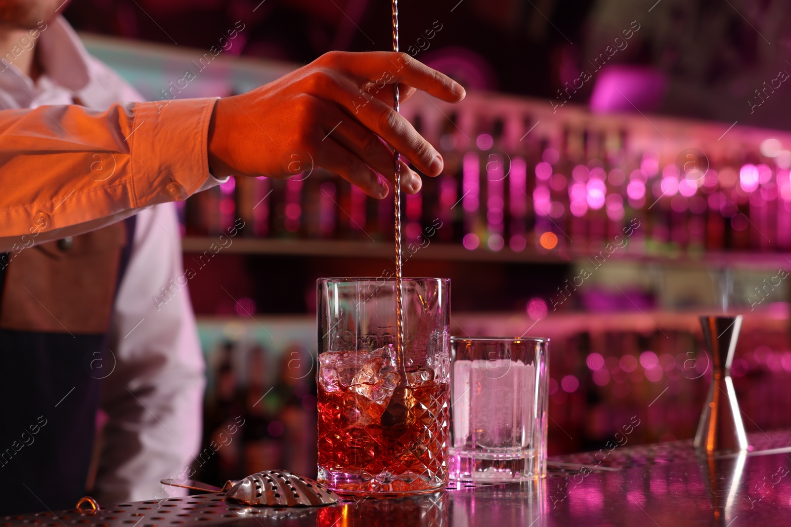 Photo of Bartender making fresh alcoholic cocktail at counter in bar, closeup