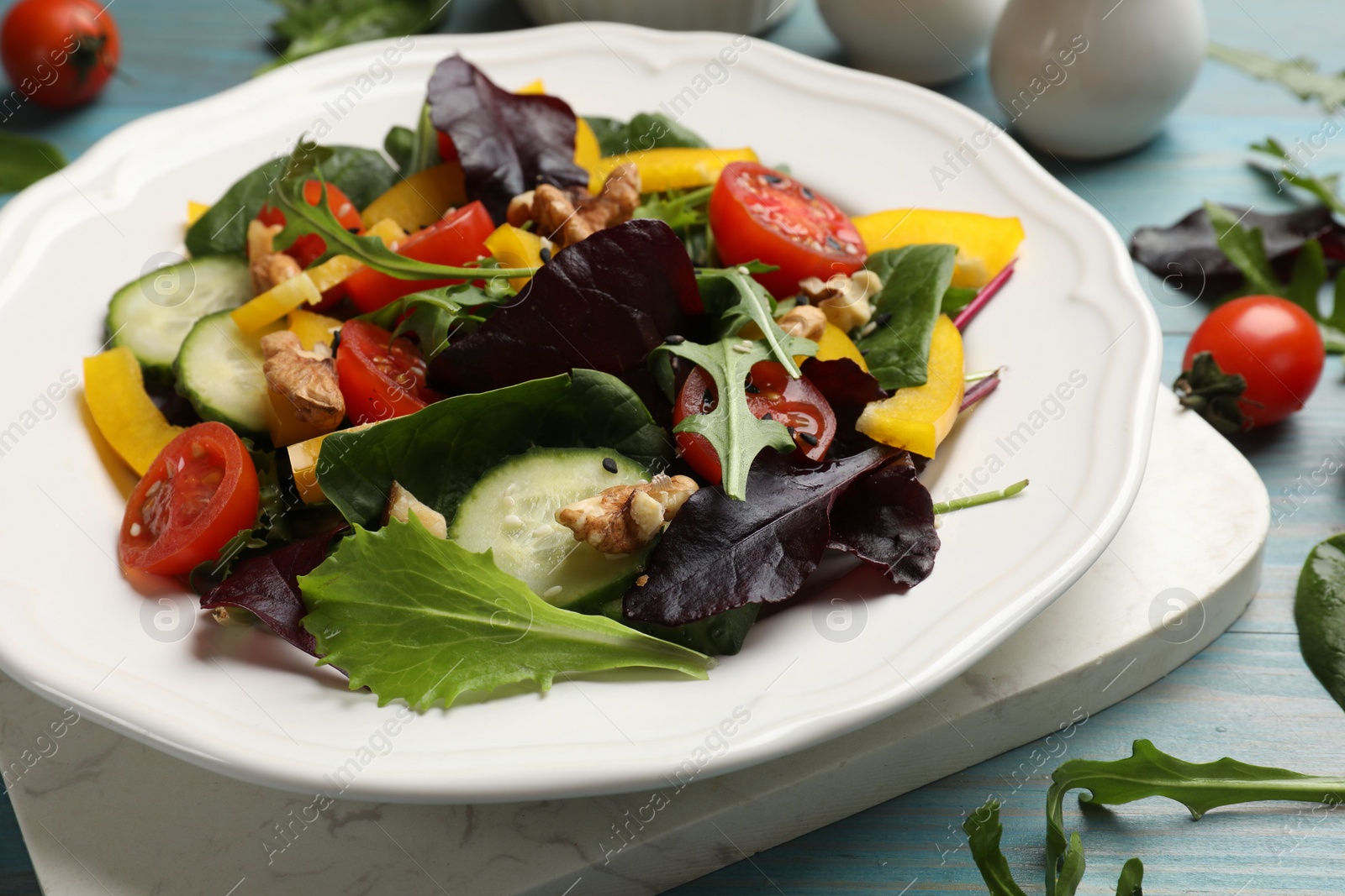 Photo of Tasty fresh vegetarian salad on light blue wooden table, closeup