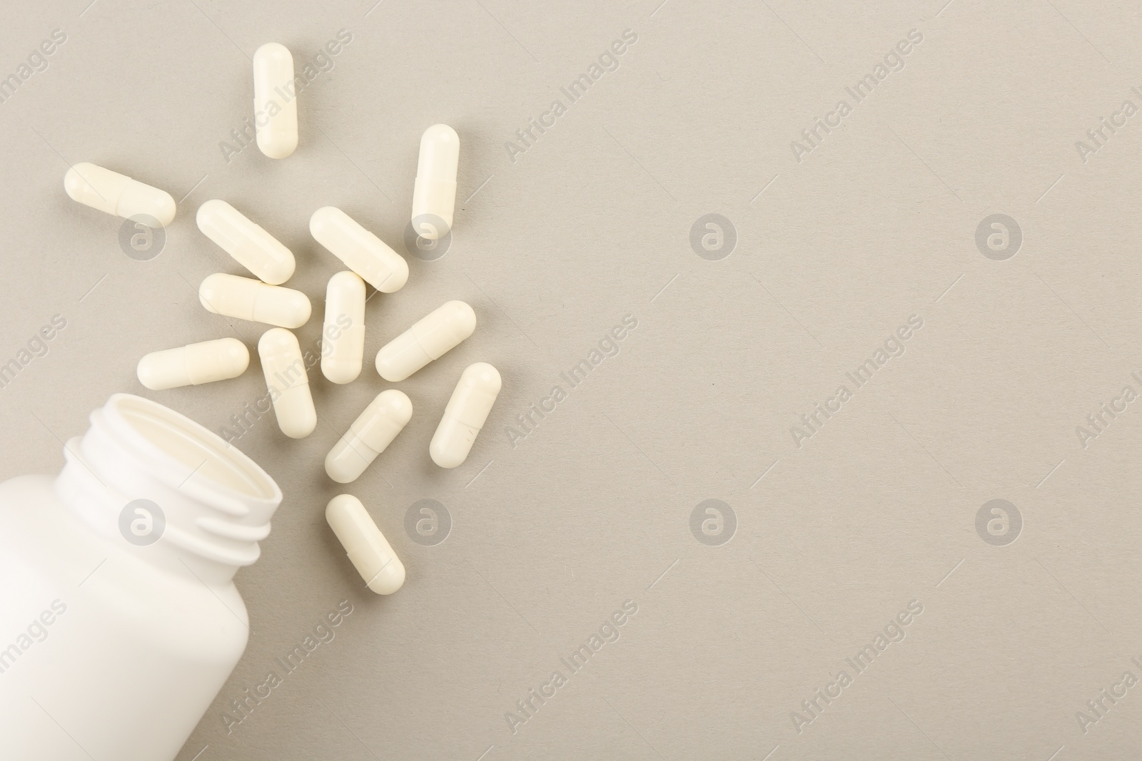 Photo of Bottle and vitamin capsules on light background, top view. Space for text