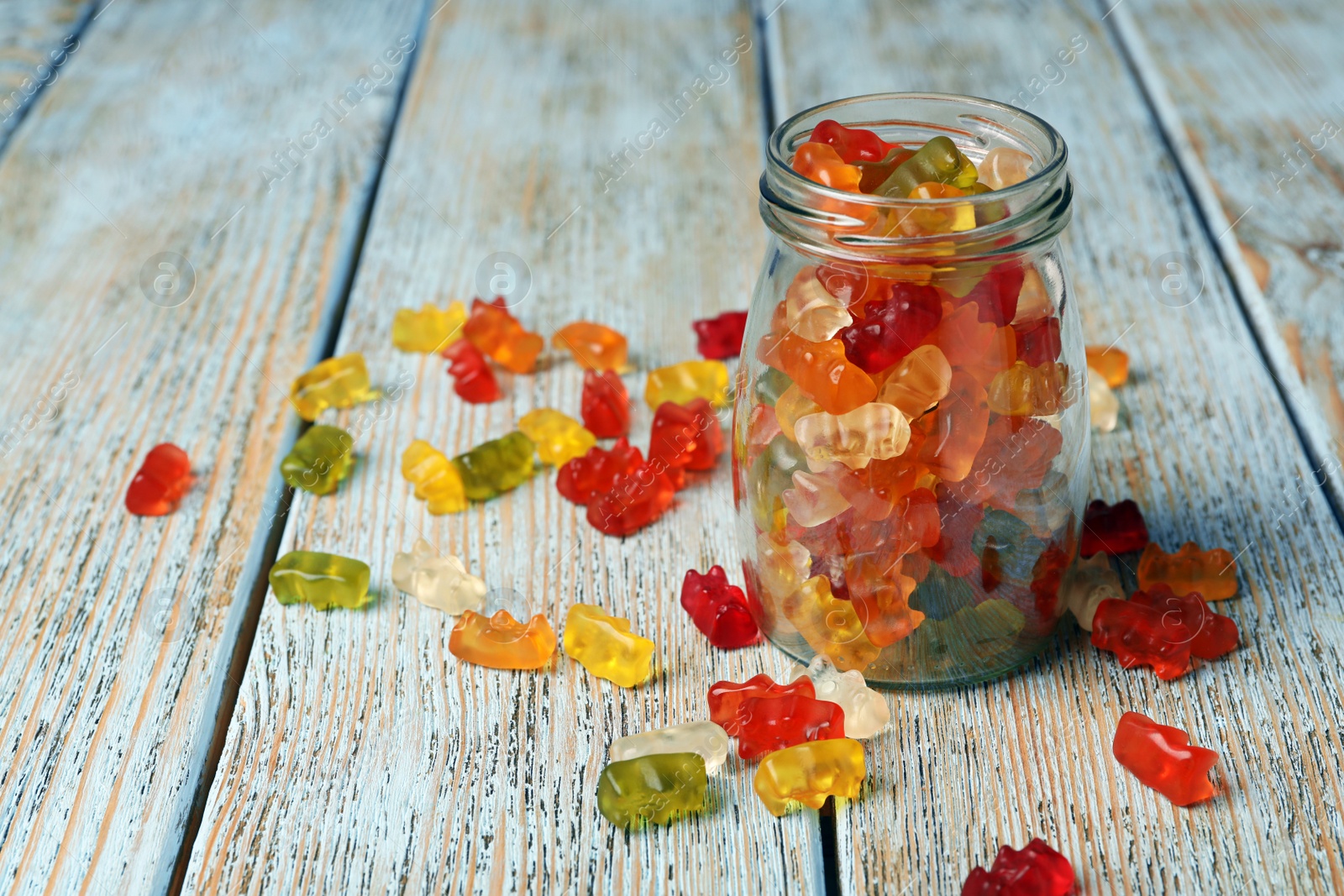 Photo of Glass jar with delicious jelly bears on wooden table. Space for text