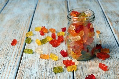 Glass jar with delicious jelly bears on wooden table. Space for text