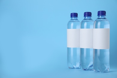 Photo of Plastic bottles with soda water on light blue background. Space for text
