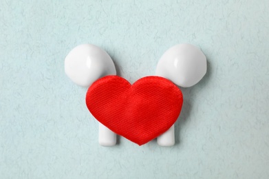 Photo of Modern earphones and red heart on turquoise background, flat lay. Listening love music songs