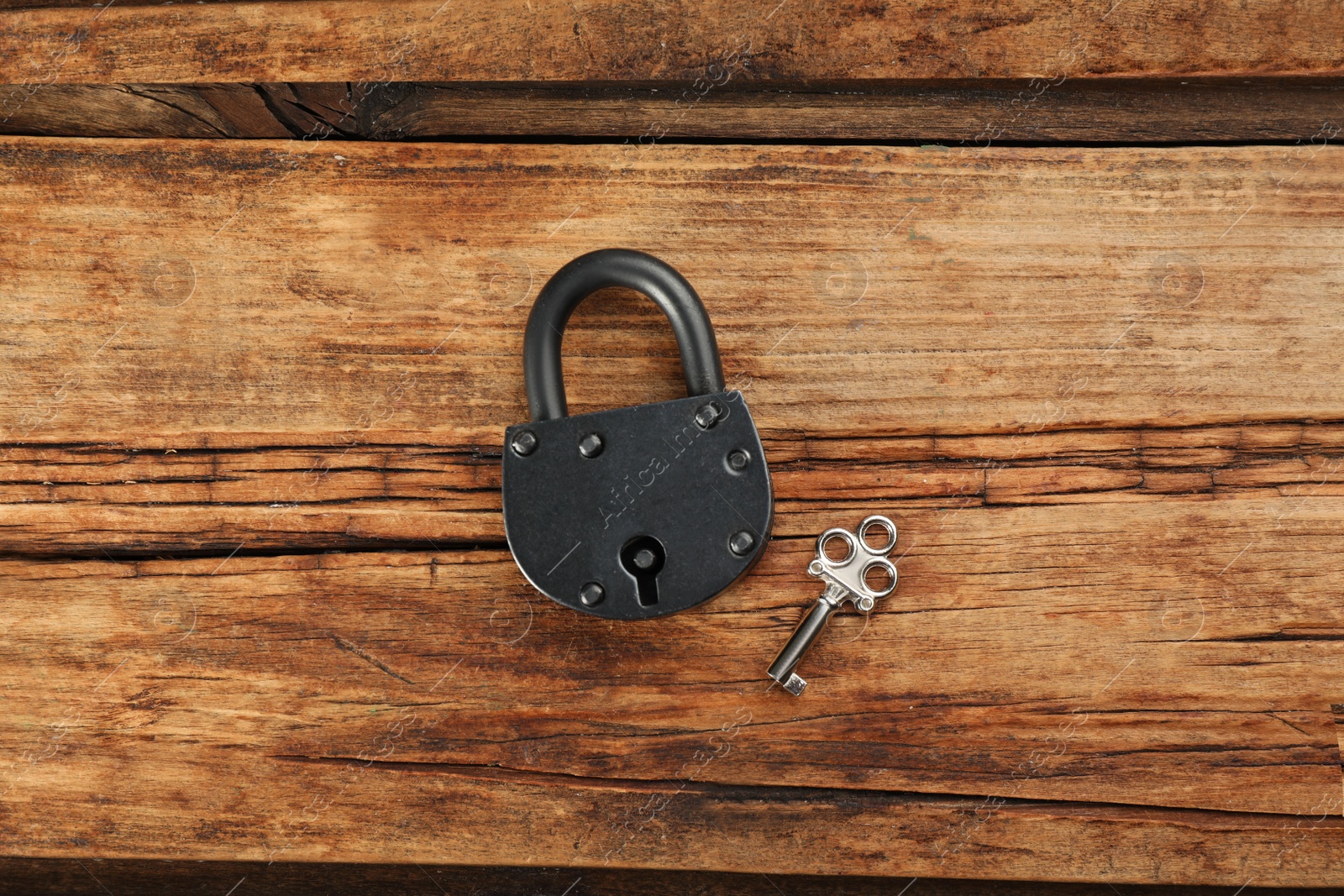 Photo of Vintage padlock with key on wooden table, flat lay