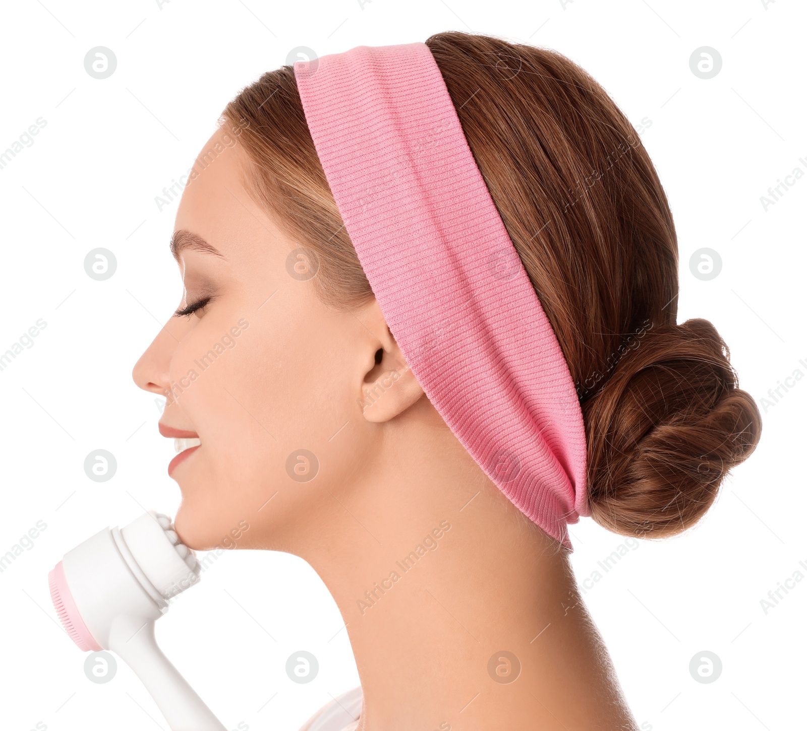 Photo of Young woman washing face with cleansing brush on white background. Cosmetic product