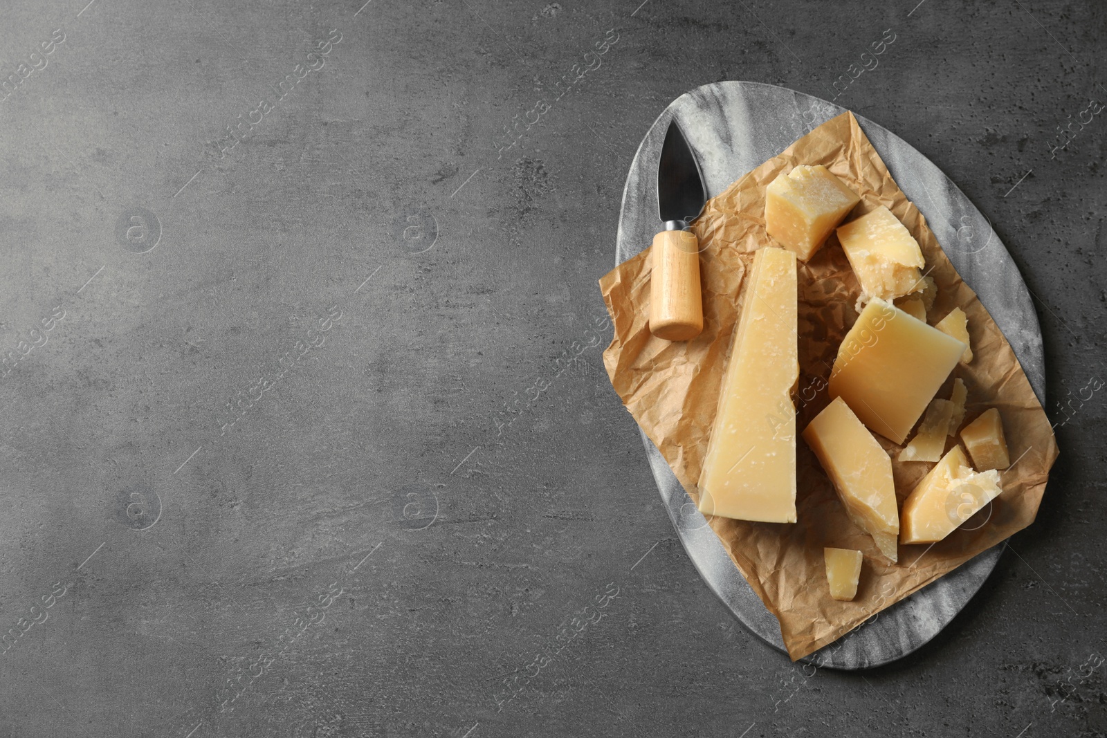 Photo of Marble board with delicious cheese on grey table, top view. Space for text