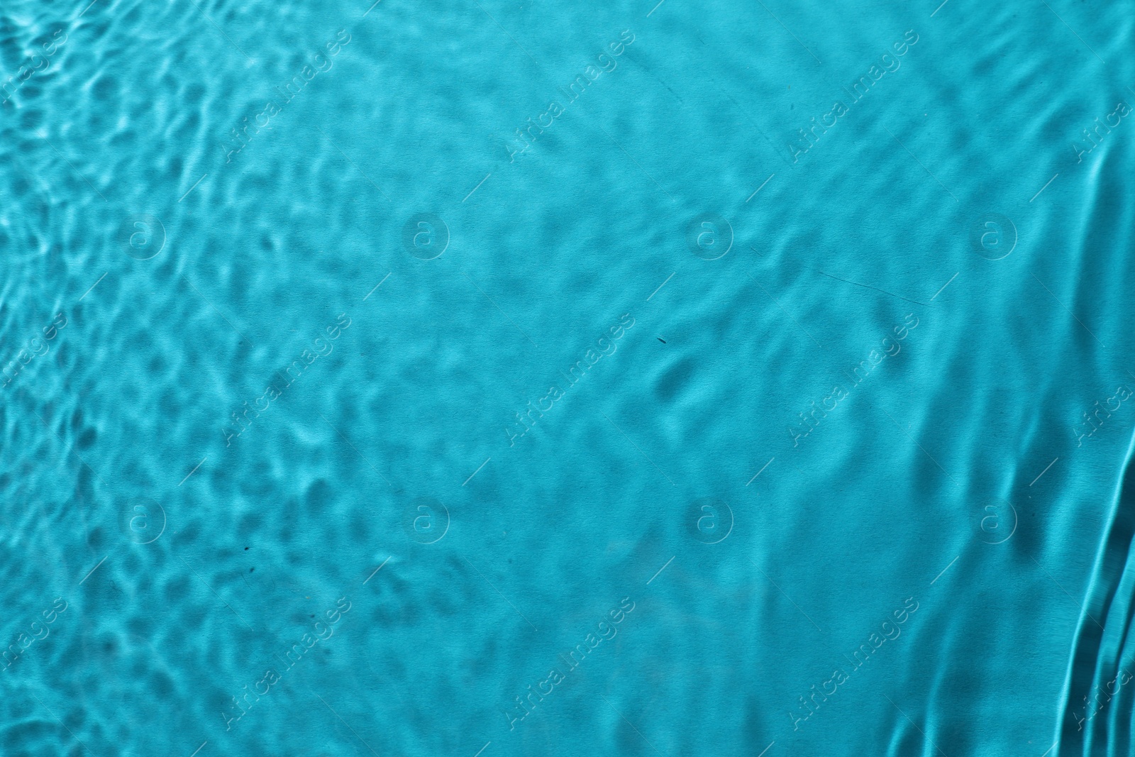 Photo of Rippled surface of clear water on light blue background, top view