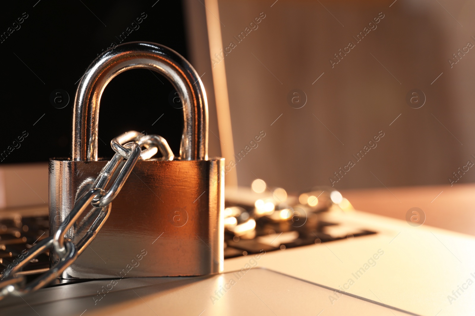 Photo of Cyber security. Laptop with padlock and chain on table, closeup. Space for text