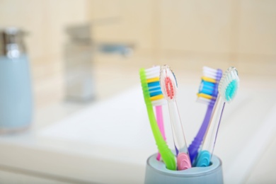 Photo of Cup with different toothbrushes near sink, closeup. Dental care