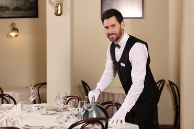 Photo of Man setting table in restaurant. Professional butler courses