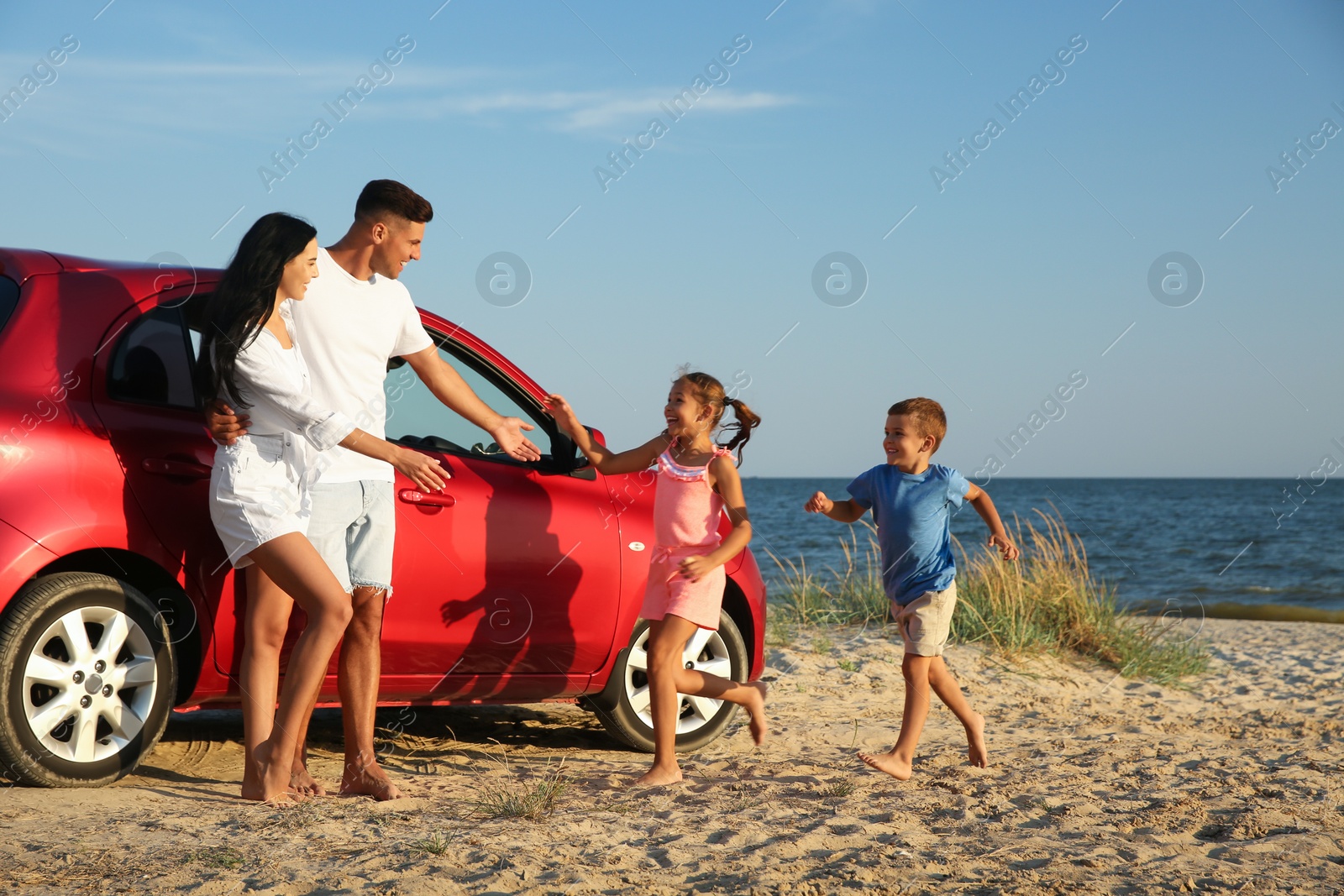 Photo of Happy children running to their parents on sandy beach. Summer trip