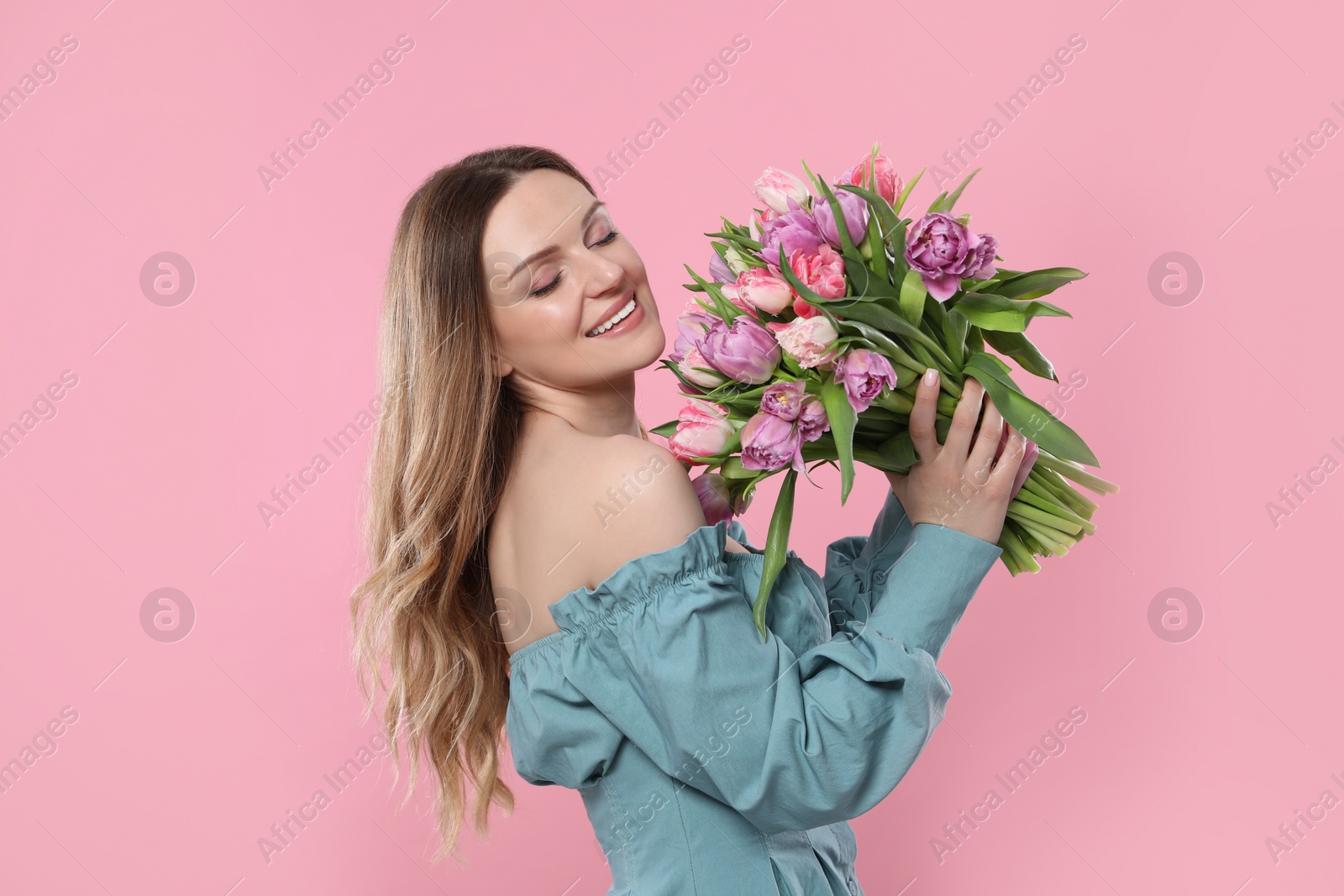 Photo of Happy young woman with bouquet of beautiful tulips on pink background