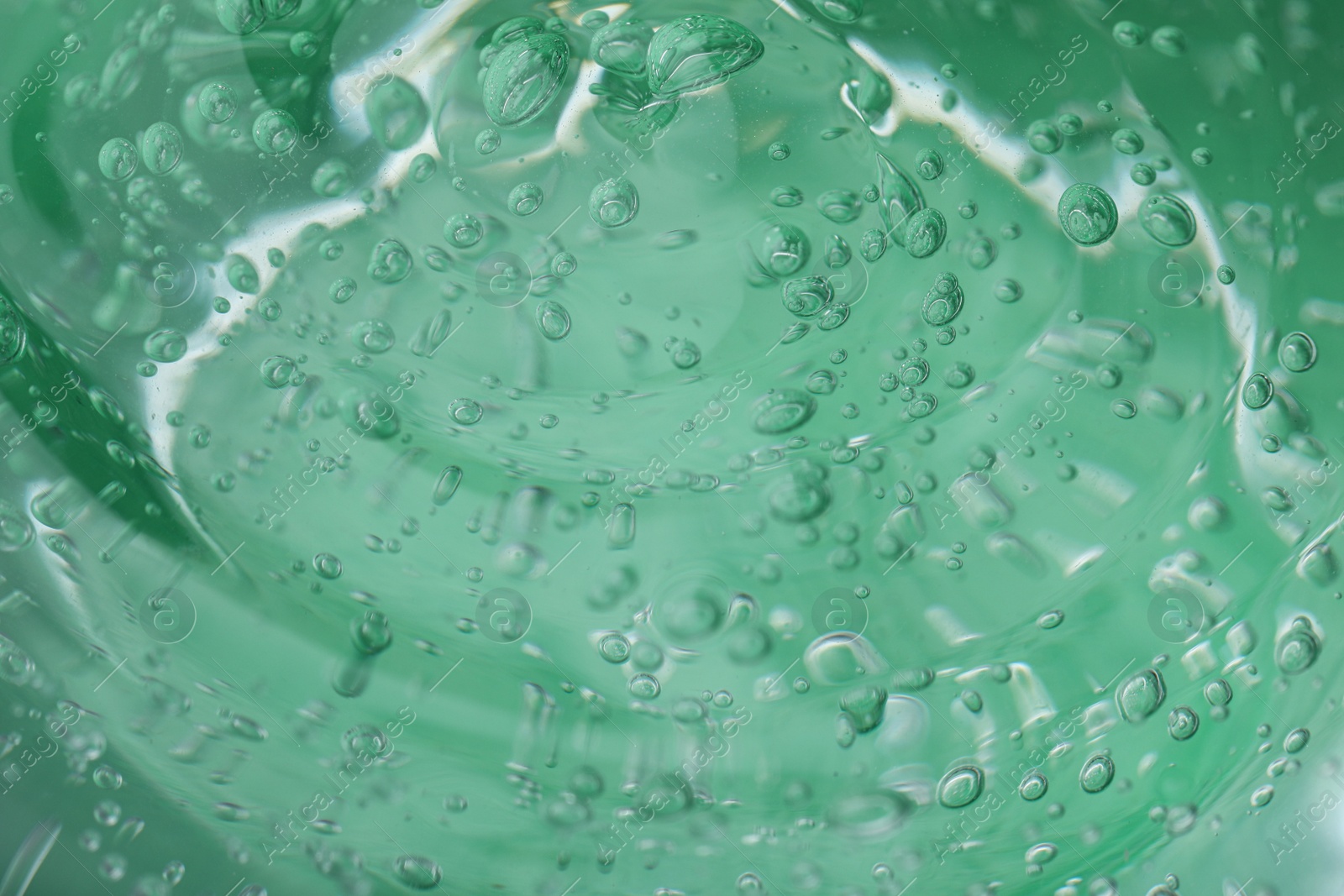 Photo of Pure transparent cosmetic gel on green background, closeup