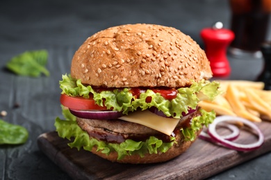 Board with tasty burger on table, closeup