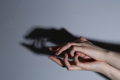 Photo of Shadow puppet. Woman making hand gesture like crocodile on grey background, closeup